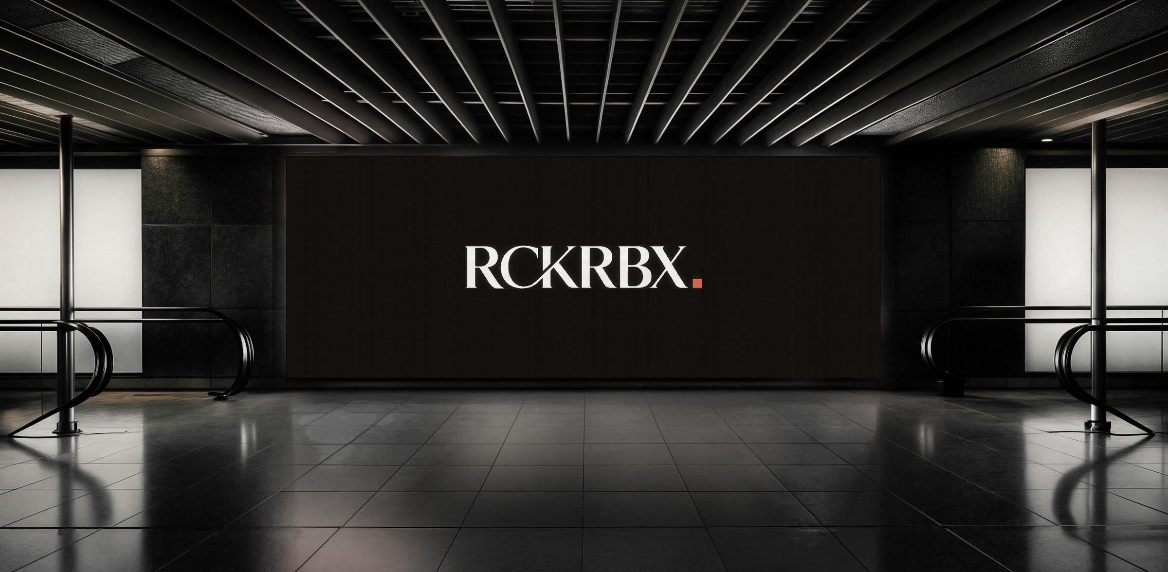 The RCKRBX wordmark on a wall-sized screen in a dark concourse