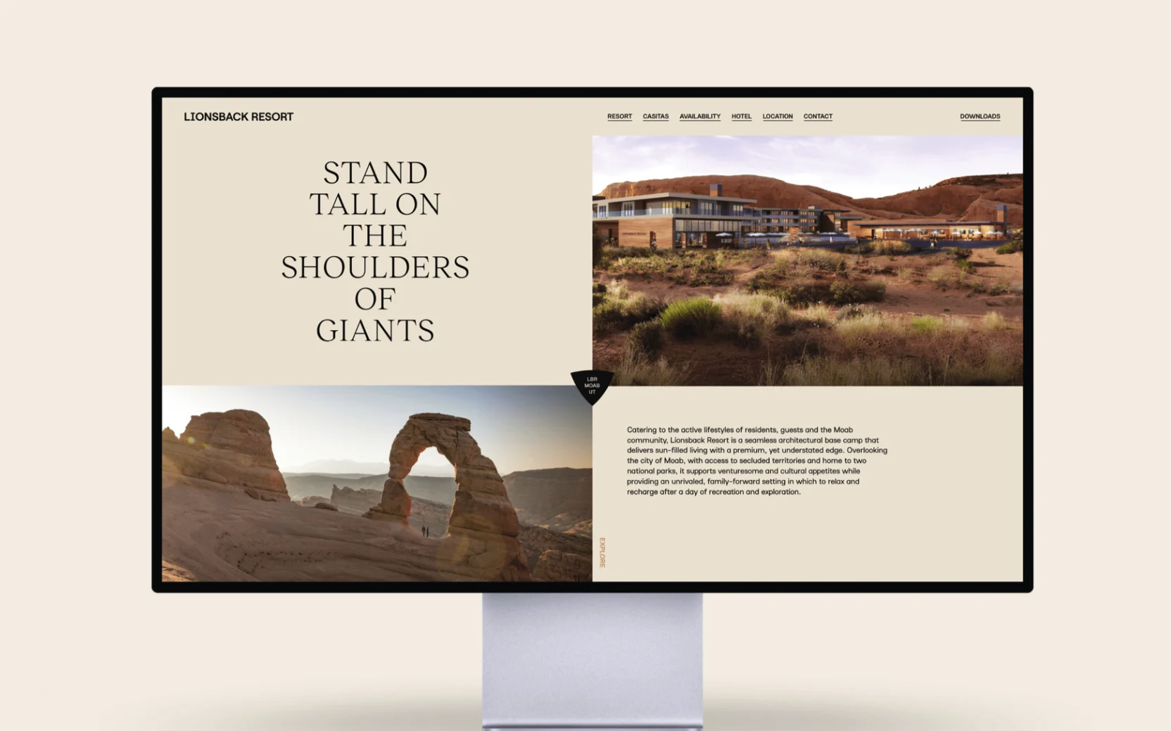 Monitor showing the Lionsback Resort website: Stand tall on the shoulders of giants in serif capitals beside the lodge rendering and Delicate Arch