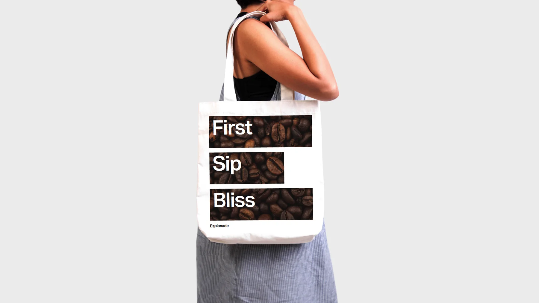 A tote bag printed with First, Sip, Bliss over coffee beans in the three-bar E