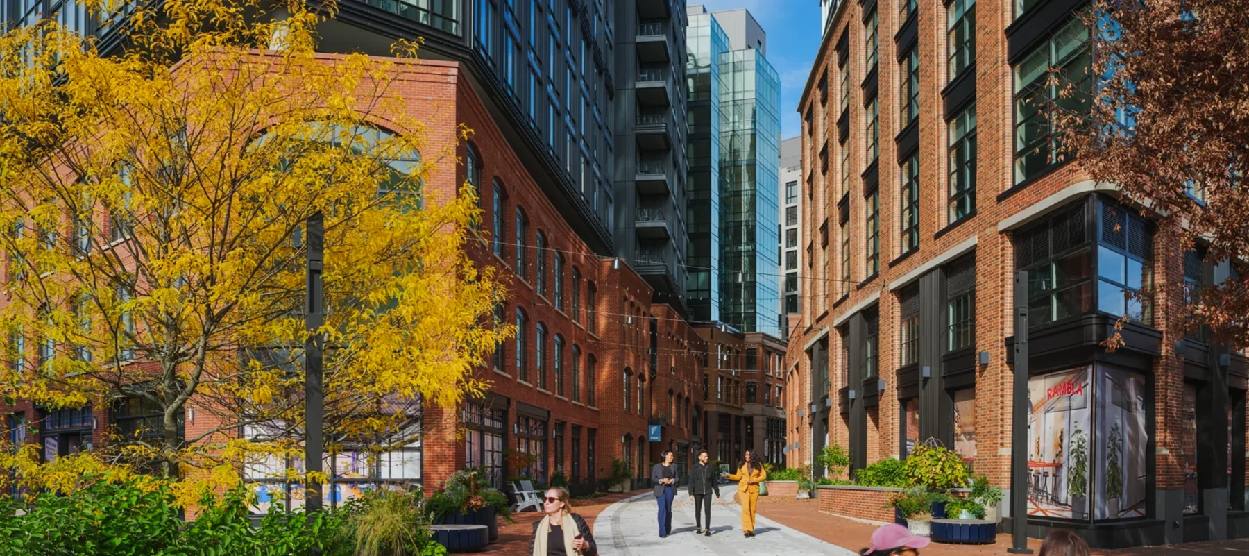 Photograph of the pedestrian street between the brick buildings in autumn, with string lights overhead