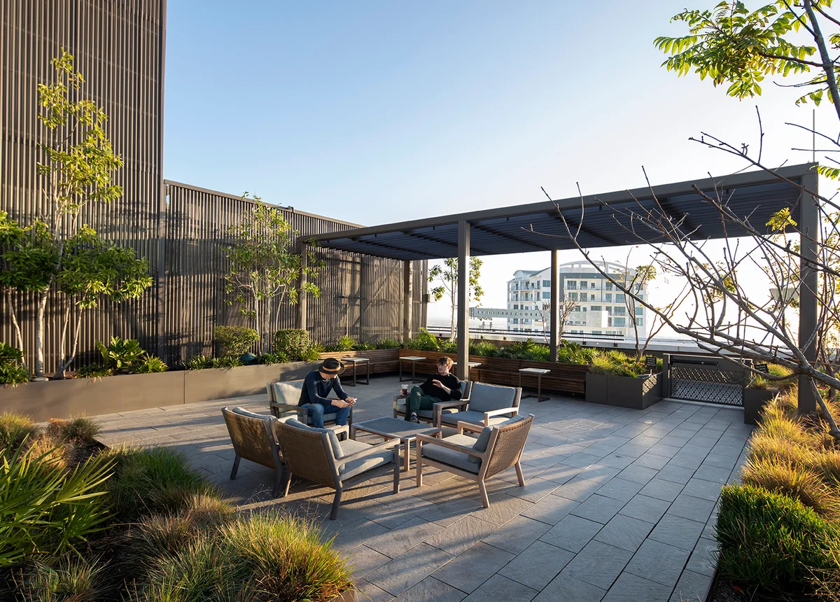 Photograph of a planted rooftop terrace at Thousand & One with a pergola, lounge seating and two people reading